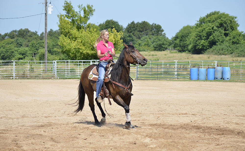 As she leaves the first barrel, Janna picks up her horse’s head and uses her legs to encourage the horse to cross over himself. This teaches her horses to finish the turn while keeping their hind end up under themselves.
