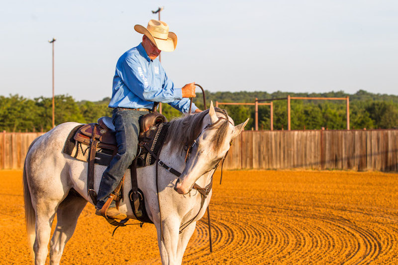 Ron Ralls adjusting reins on horse for circle