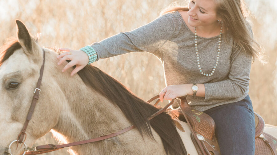 girl horseback petting horse's mane