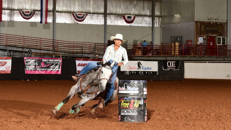 girl turning a barrel on grey horse