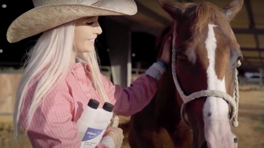 rider standing with horse that has water drinking problems