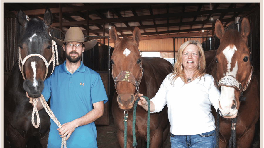 Robin Weaver and Brandon Cullins standing with their horses in barn aisle