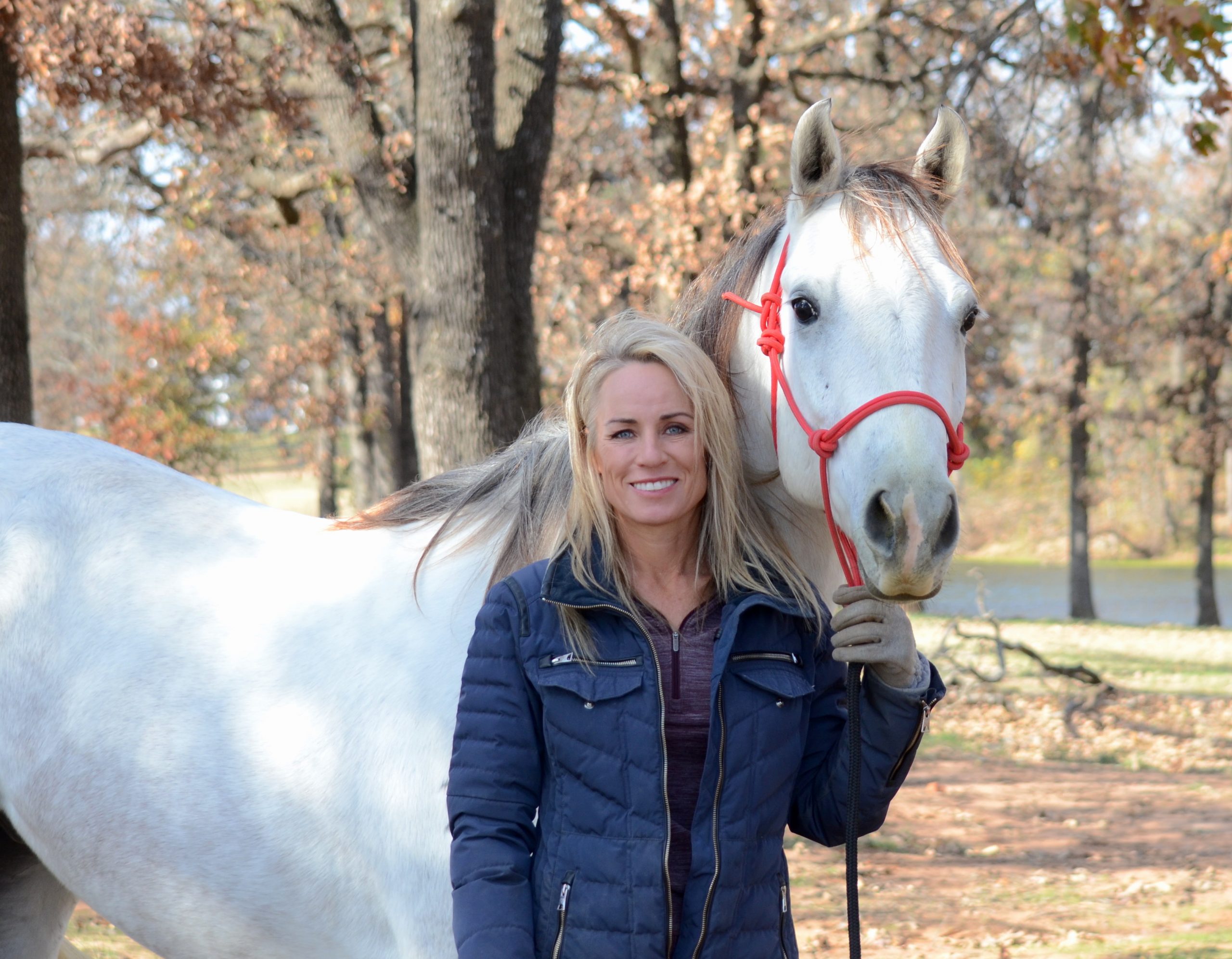 Danyelle Campbell with grey horse in wooded area