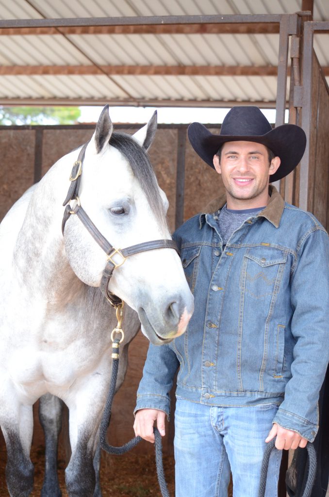 Kyle Leleux standing next to gray horse