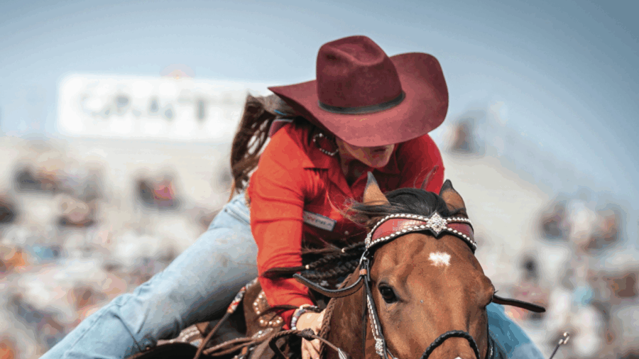 close-up of girl on horse running out of arena