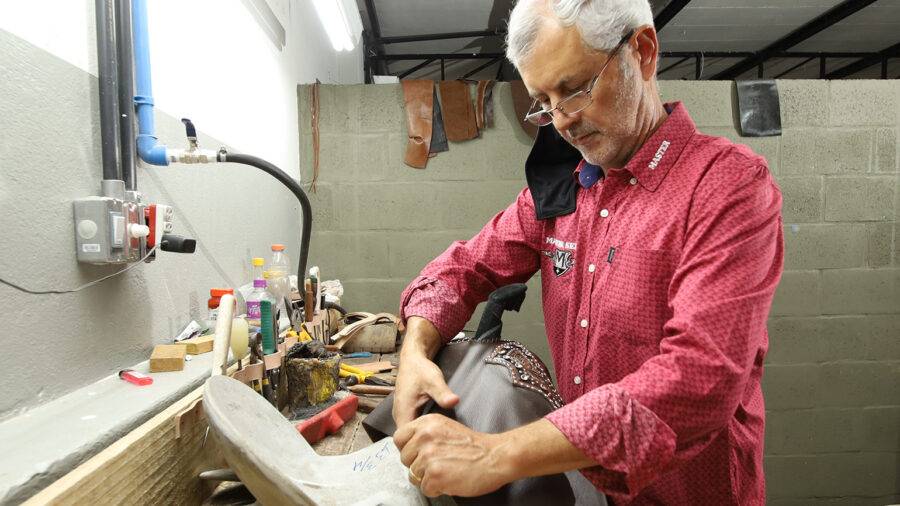 saddle maker wrapping leather on saddle tree