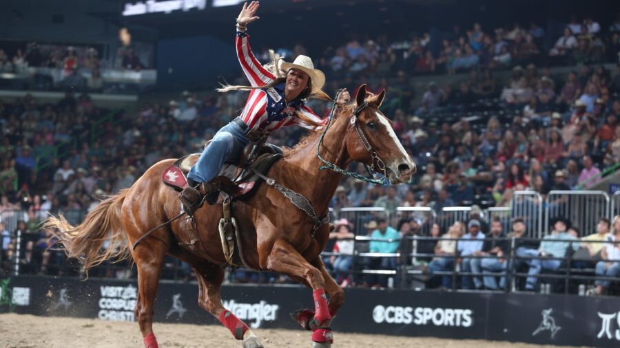 girl on horse waving at crowd in rodeo