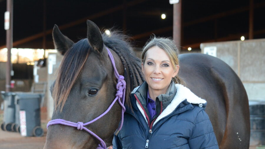 Kassie Mowry standing with brown gelding at stalls