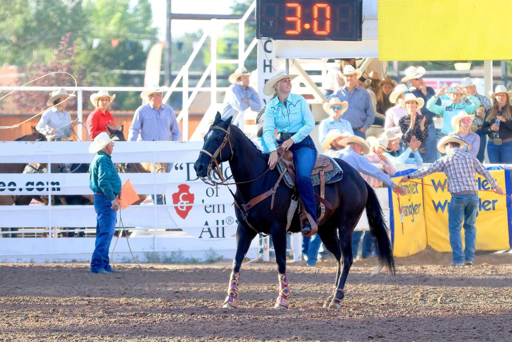 Peggy Garman patting horse's neck after roping at Cheyenne Frontier Days