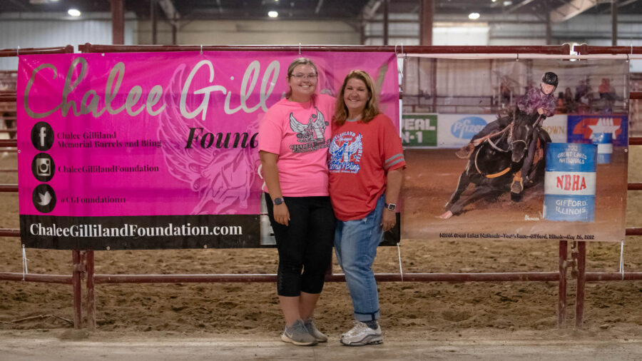 Two women pose by banner