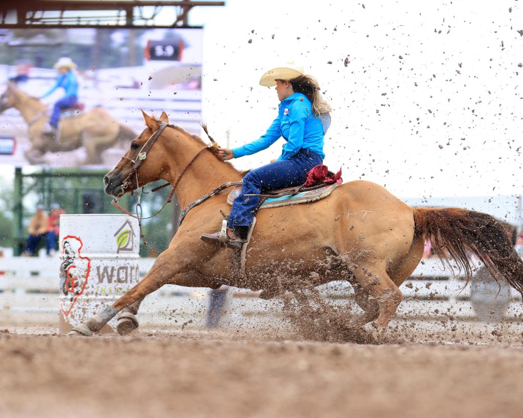 girl turning a barrel at Cheyenne in the mud