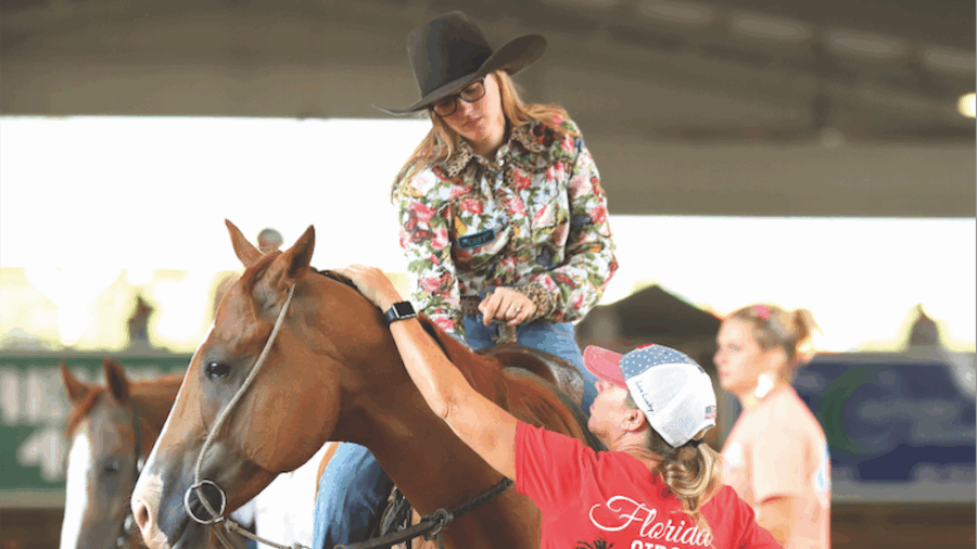 woman helping girl on horse